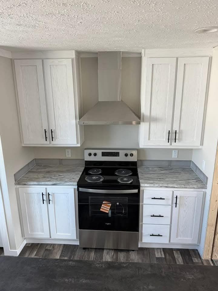 Compact modern kitchen with white cabinets, stainless steel oven and range hood, and gray marbled countertops. A functional and sleek design.
