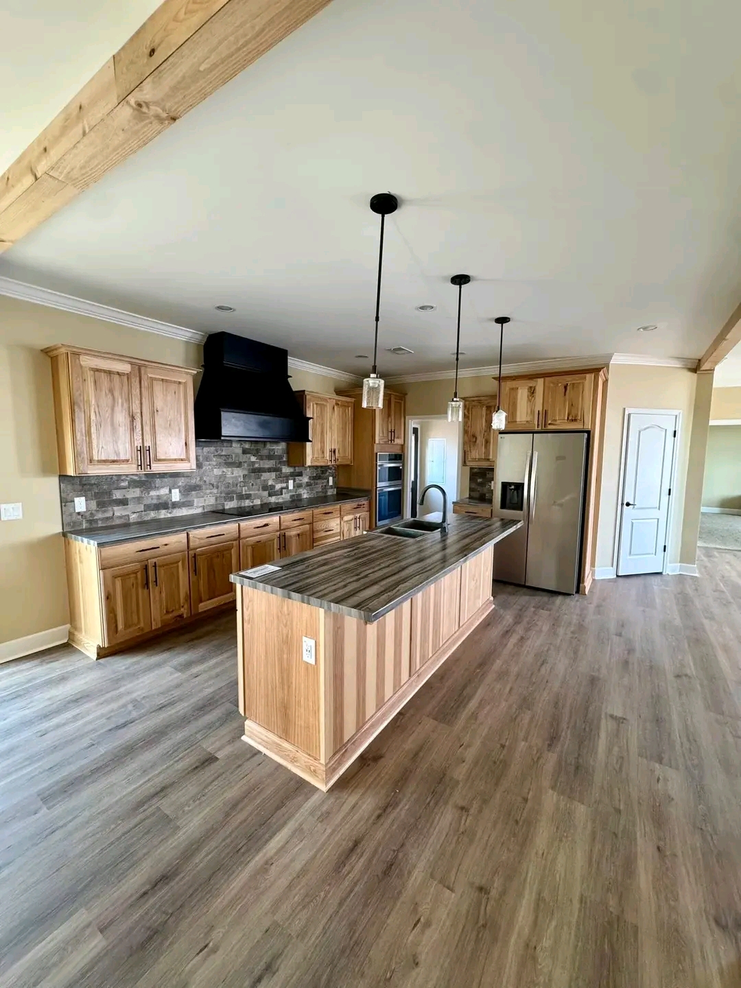 Spacious kitchen with wooden cabinets, a sleek island, stainless steel appliances, and pendant lights, exuding a modern and welcoming feel.