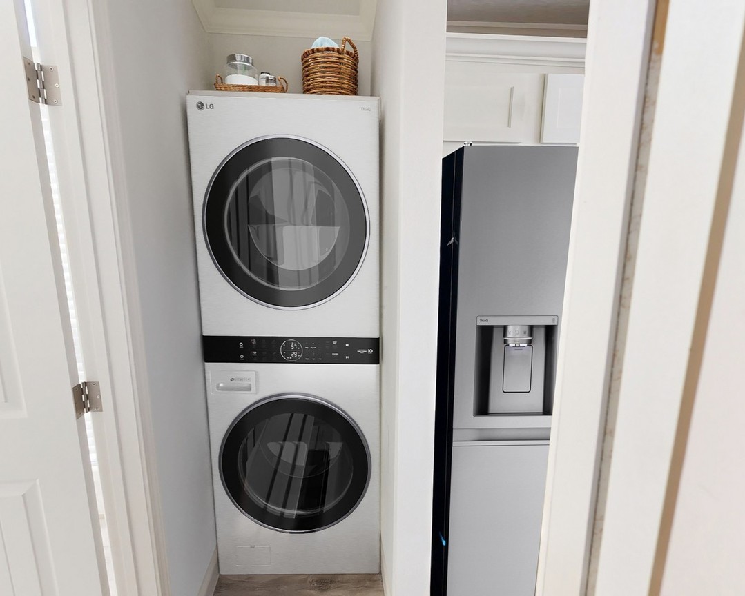 Modern laundry nook with stacked LG washer and dryer, adjacent to a sleek silver fridge. A woven basket and jar decorate the space above.