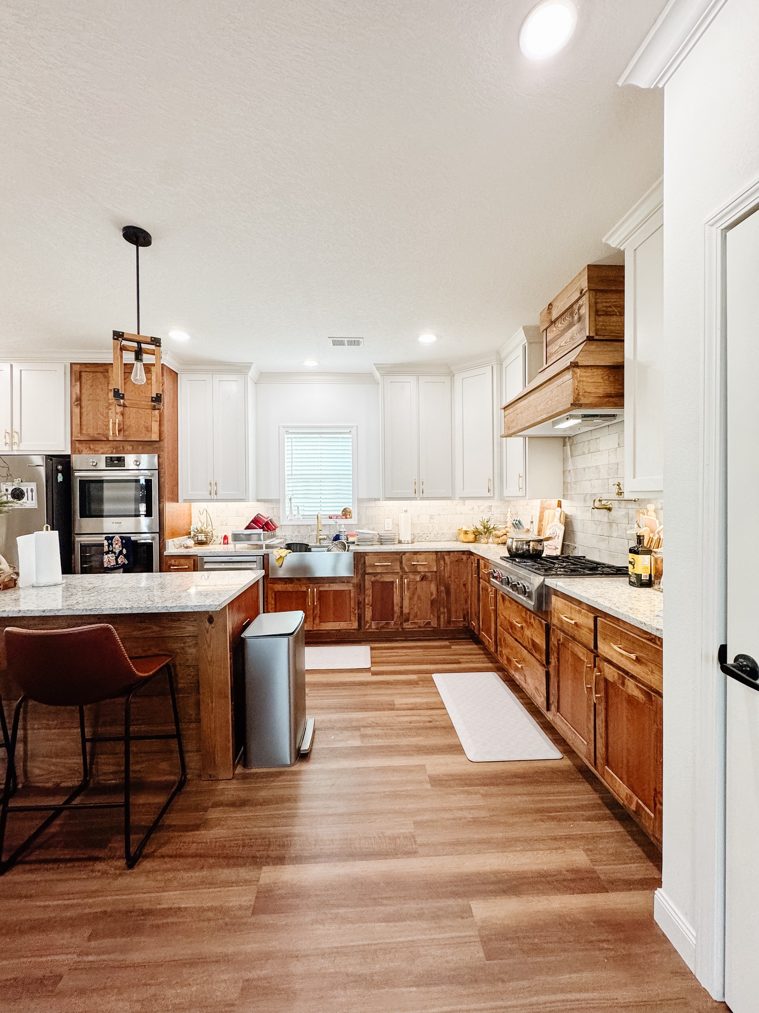 Spacious kitchen with wooden cabinets, white countertops, and stainless steel appliances. Warm lighting creates an inviting, cozy atmosphere.