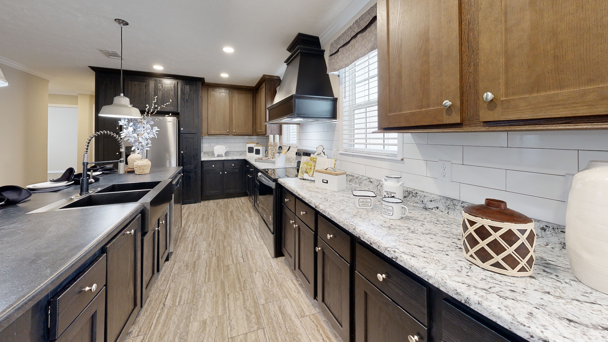 Spacious kitchen with dark wood cabinets and granite countertops. Features a black sink, modern appliances, pendant light, and decorative accents. Cozy ambiance.