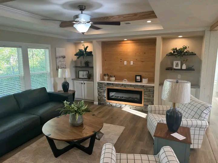 Stylish living room with a dark sofa, two plaid chairs, and a wooden coffee table. A modern fireplace is set in a stone accent wall. Cozy, elegant decor.
