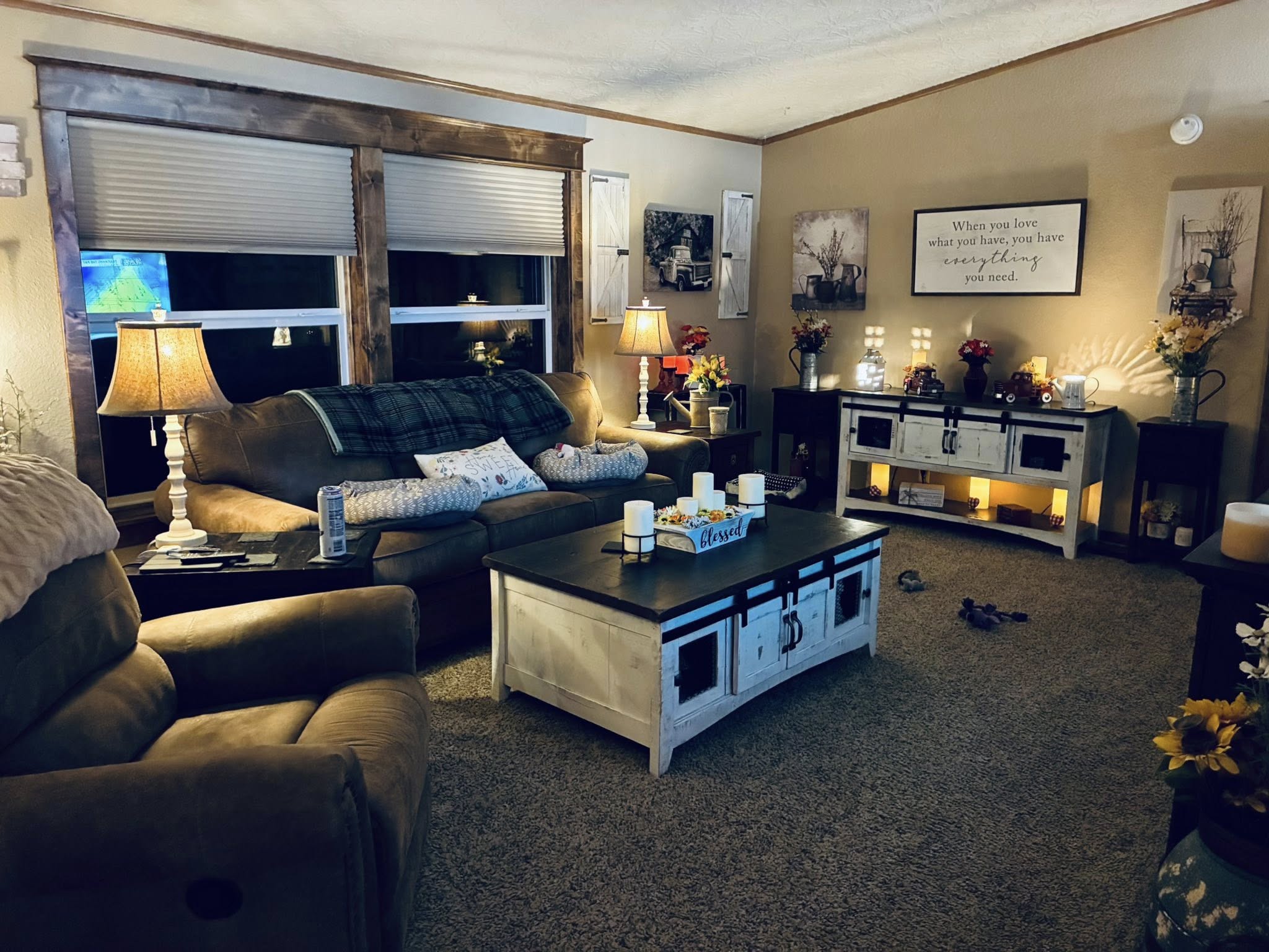 Cozy living room with soft lighting features a plush sofa, armchair, rustic wooden coffee table, and ambient lamps. Warm, inviting tones create a relaxed atmosphere.