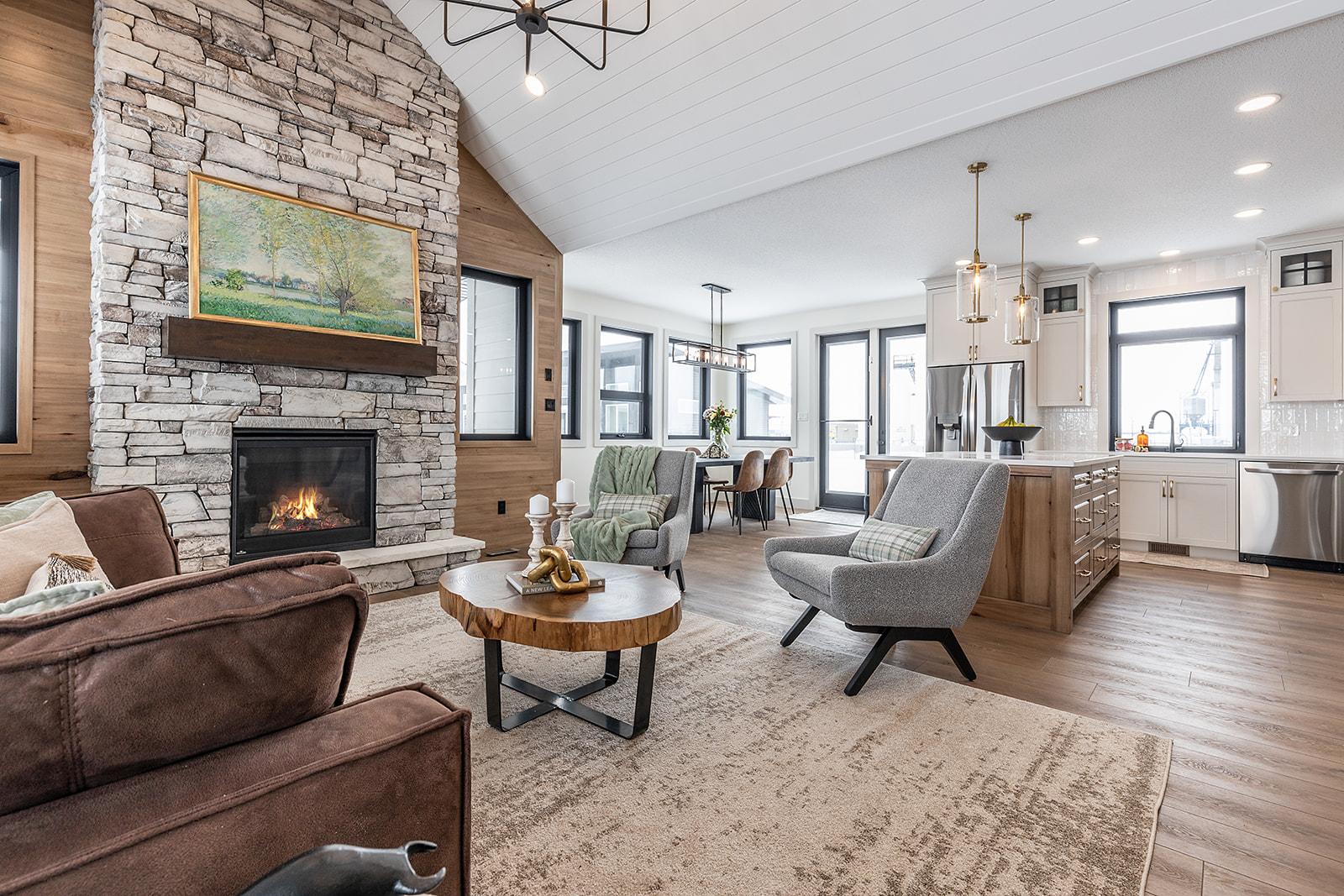 A modern, cozy living room with a stone fireplace, abstract art, and a warm fire. Stylish seating and a rustic coffee table create an inviting atmosphere.