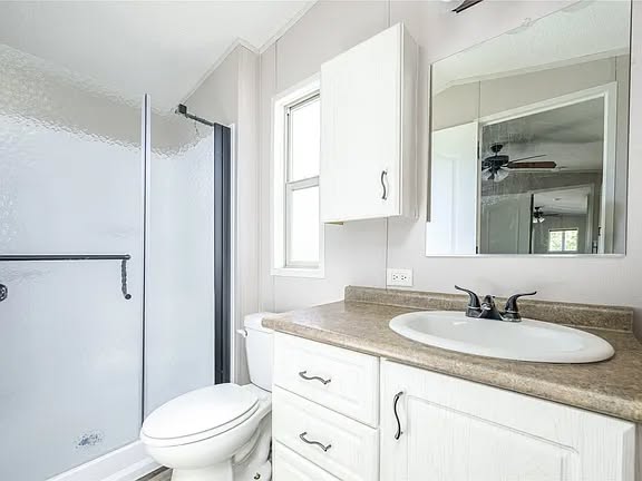 Bright, modern bathroom with white cabinets, a brown countertop, and a sleek faucet. A glass shower door is on the left, creating a clean, airy feel.