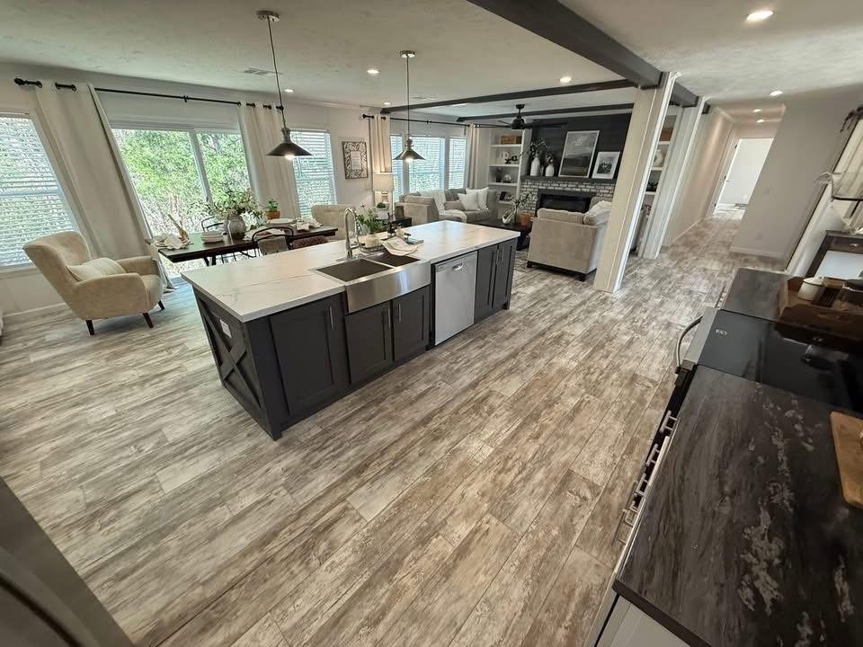 Spacious open-concept kitchen and living area with wood flooring. Features a large island, cozy seating, modern decor, and bright natural light.