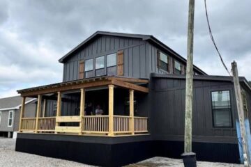 Large, dark gray two-story house with a wooden porch under overcast skies. Text overlay states: Price $41,000, Down Payment $2,500. Gravel foreground.