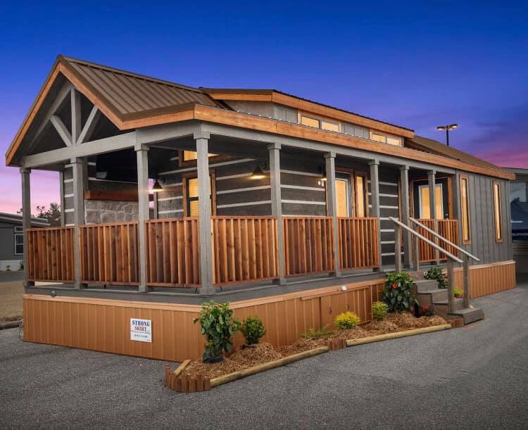 A cozy cabin under a twilight sky, featuring a rustic wooden porch and warm interior lighting. The scene conveys a tranquil, inviting atmosphere.