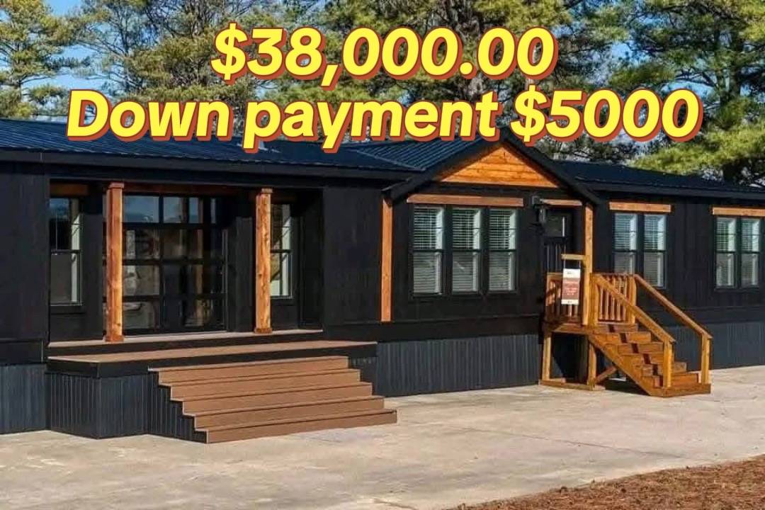 Modern, dark-toned modular home with wooden accents, large windows, and steps leading to a porch. Overlaid text: "$38,000.00, Down payment $5,000."