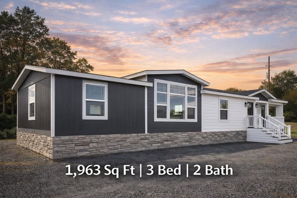 A modern manufactured home with a stone and dark siding exterior is shown at sunset, featuring large windows and a porch. Text reads "1,963 Sq Ft | 3 Bed | 2 Bath."