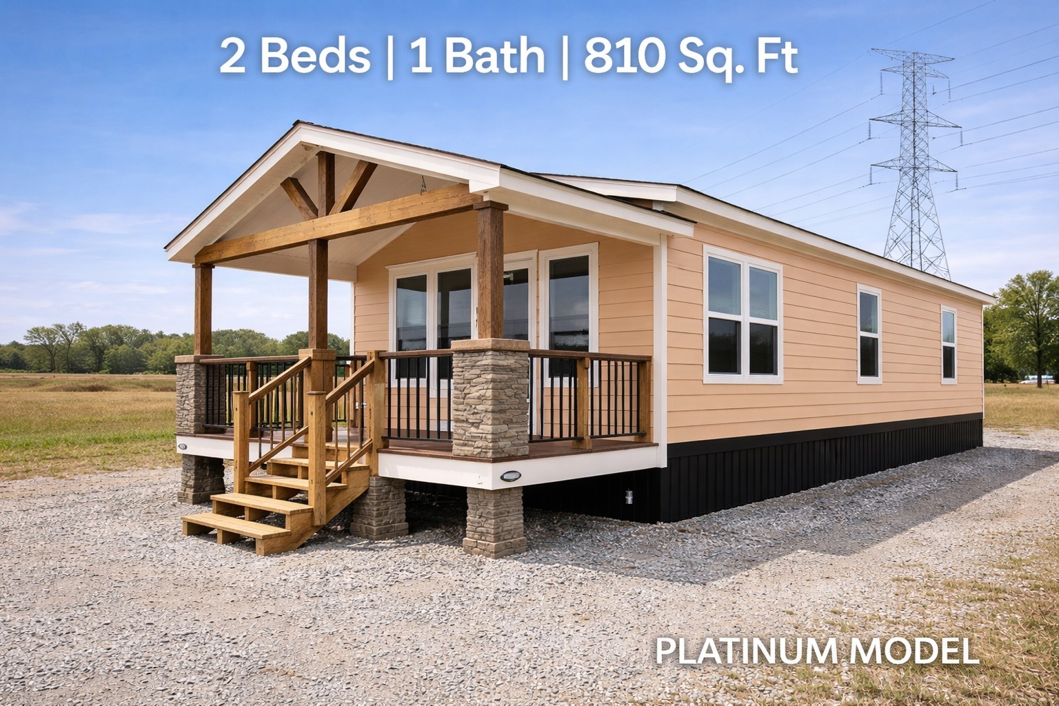 Compact beige modular home with wooden porch on a gravel lot, labeled "2 Beds | 1 Bath | 810 Sq. Ft, Platinum Model" under a clear blue sky.