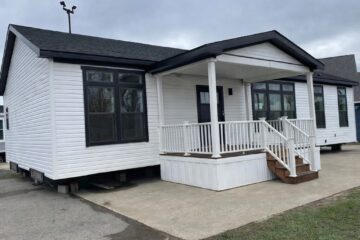 White modular home with black roof and large windows, featuring a small covered porch with railings. Text reads: "3 Beds | 2 Baths | 1,920 sq. ft."