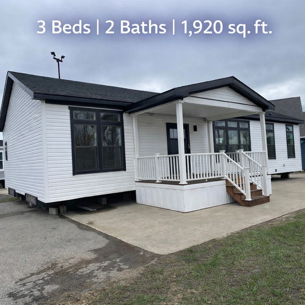 White modular home with black roof and large windows, featuring a small covered porch with railings. Text reads: "3 Beds | 2 Baths | 1,920 sq. ft."