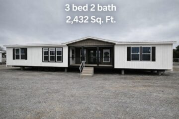 A large white modular home with two sections and a central porch on a gravel lot. Text reads: "3 bed 2 bath 2,432 Sq. Ft." over a cloudy sky.