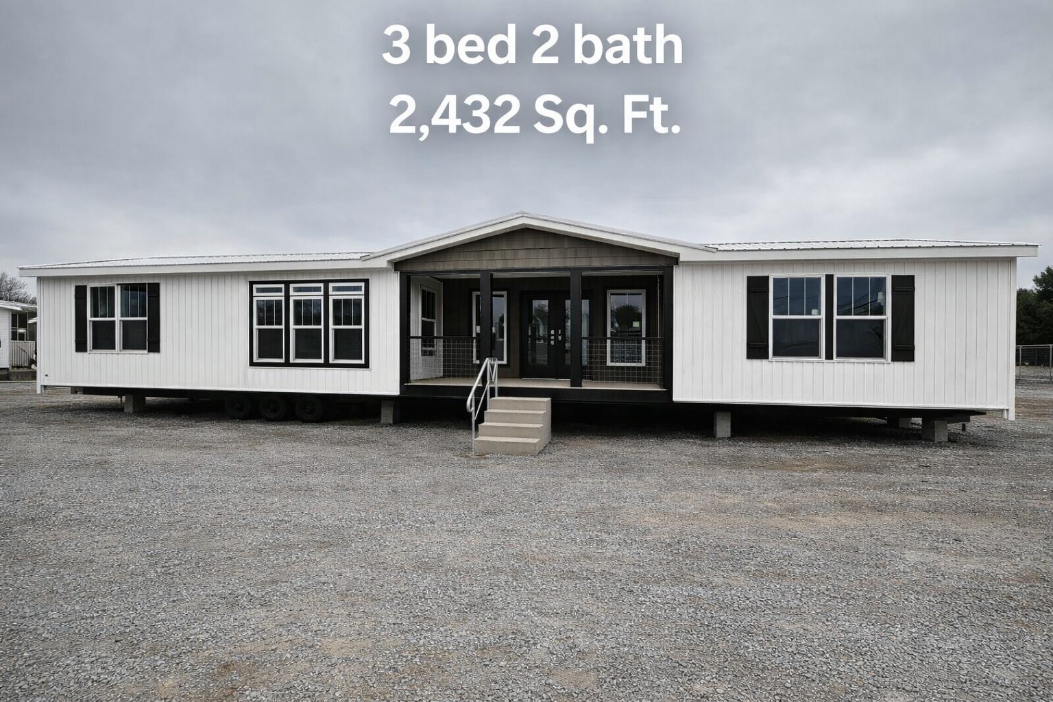 A large white modular home with two sections and a central porch on a gravel lot. Text reads: "3 bed 2 bath 2,432 Sq. Ft." over a cloudy sky.