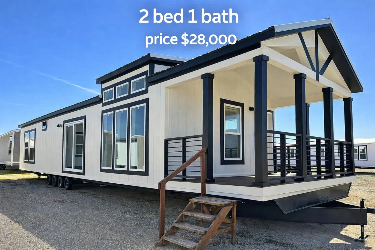 Modern white mobile home with black trim, front porch, and large windows. Text reads "2 bed 1 bath, price $28,000." Bright, clear day.