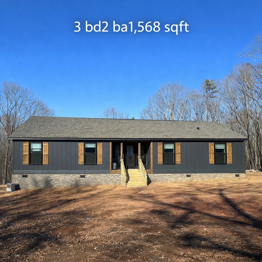 Single-story dark gray house with wooden shutters, set against a clear blue sky and sparse wooded area. Text reads "3 bd, 2 ba, 1,568 sqft."