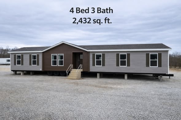 A large, single-story manufactured home exterior with gray and brown siding is shown on a gravel lot. Text above reads "4 Bed 3 Bath, 2,432 sq. ft."