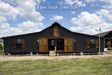 A modern, dark gray barn-style house with wooden shutters and large sliding doors is set against a blue sky with clouds. Text: "4 bed 2 bath, 2,460 SQFT."