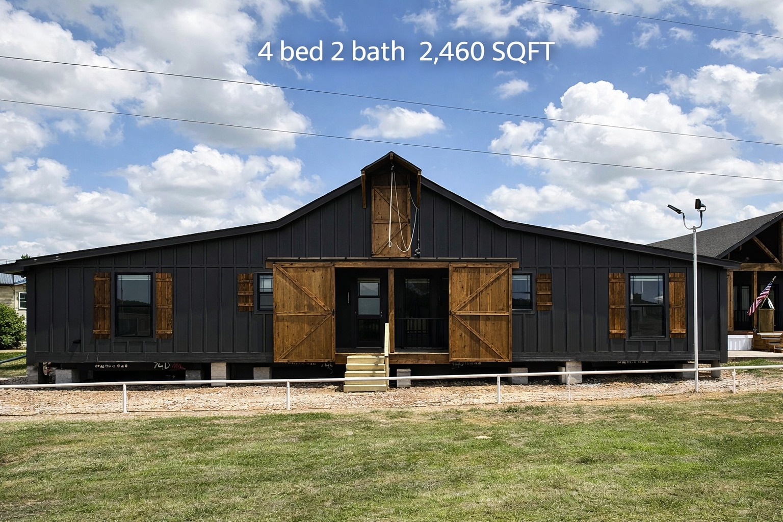 A modern, dark gray barn-style house with wooden shutters and large sliding doors is set against a blue sky with clouds. Text: "4 bed 2 bath, 2,460 SQFT."
