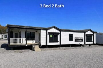 A white mobile home labeled "Southern Charm" with a small porch and steps is set against a clear blue sky. Text reads “3 Bed 2 Bath.” Gravel surrounds the home.
