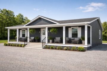 A modern gray ranch-style house with a white trim and a front porch featuring black railings. Potted ferns hang above seating areas. The sky is clear.