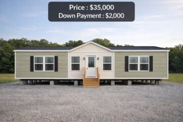 A beige and white mobile home with black shutters sits on a gravel lot, surrounded by trees under a clear sky. Price: $35,000, Down Payment: $2,000.