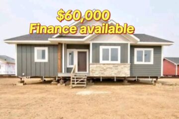 A gray modular home with a stone accent under the windows stands on a dirt lot. Text above reads "$60,000 Finance available" in bold yellow.