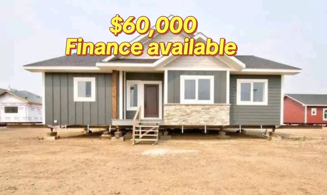A gray modular home with a stone accent under the windows stands on a dirt lot. Text above reads "$60,000 Finance available" in bold yellow.
