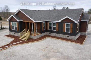 Single-story house with gray roof, dark siding, and wooden accents. It features a small porch and steps, surrounded by gravel. Text: "3 Bedrooms | 2 Bathrooms | 2,089 sqft."