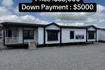 Manufactured home labeled "Southern Charm" with white siding and black trim. Price: $55,000, Down Payment: $5,000. Set on gravel lot under a blue sky.