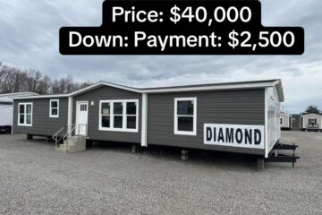 Gray mobile home displayed on a gravel lot with overcast sky. Sign reads "Diamond." Text at top states price of $40,000 and down payment of $2,500.